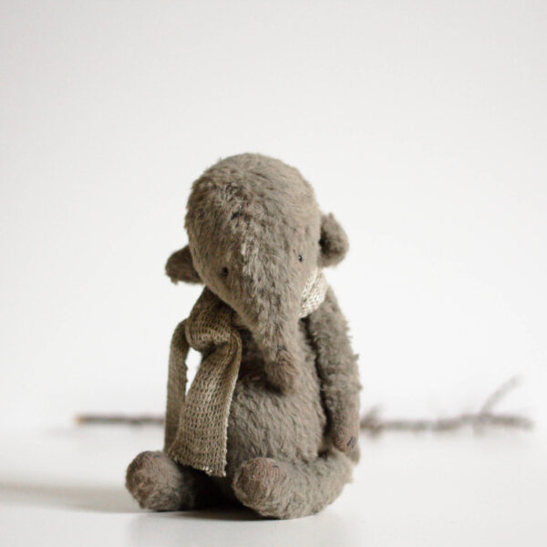 gray mohair plush elephant with scarf sitting on desk