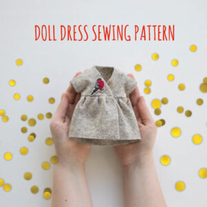 festive felt doll dress with red bird embroider in hands