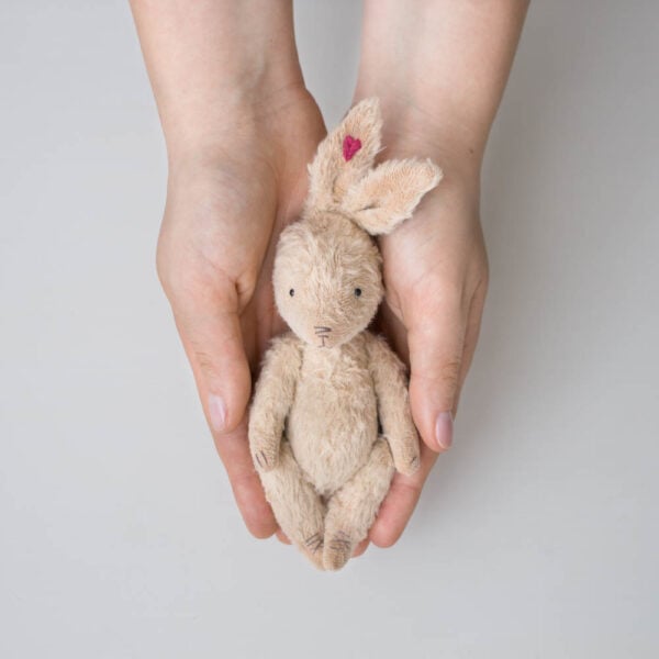 beige mohair plush bunny with heart embroidery on ear in hands