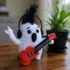 Rockstar ghost amigurumi plushie made with white and black yarn, wearing a tiny guitar and sunglasses. Fun Halloween crochet toy, perfect for spooky handmade gifts or DIY home decor. Ideal for beginners looking for easy, stylish amigurumi projects.