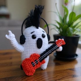 Rockstar ghost amigurumi plushie made with white and black yarn, wearing a tiny guitar and sunglasses. Fun Halloween crochet toy, perfect for spooky handmade gifts or DIY home decor. Ideal for beginners looking for easy, stylish amigurumi projects.