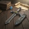 A handmade crochet sword with a gray blade, blue and white accents, and a yellow dragon eye at the center of the hilt. The plush sword is held in one hand and rests on a large outdoor rock, combining fantasy aesthetics with a soft, toy-like design.