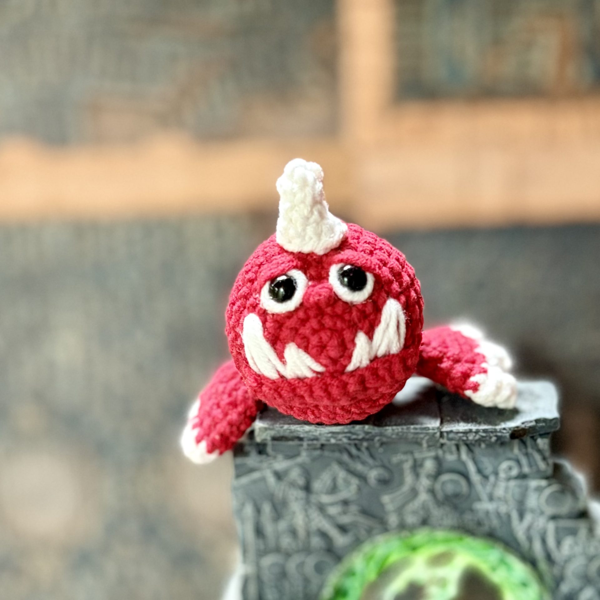Pocket Squig Crochet Pattern. Warhammer Fantasy Amigurumi PDF 7 Crochet pattern featuring a small red Warhammer Squig resting on top of ancient stone ruins above a glowing green portal